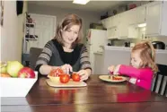  ?? ROBERT LEITCH/ THE ASSOCIATED PRESS ?? Shannon McCormick cuts up a tomato for her daughter Sophie at their home in Ohio.