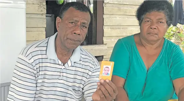  ?? Photo: Nacanieli Tuilevuka ?? Isa na vuaku (My grandson gone too soon) .... Apenisa Rawqa holds a picture of Apenisa Rawaqa (Junior) at Navua while Navireta Navinoni looks on September 17, 2018.