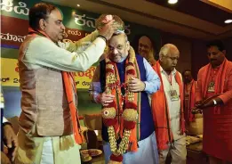  ?? — PTI ?? BJP national president Amit Shah being presented a Mysore peta by Union minister Ananth Kumar during his meeting with the party's state legislator­s and MPs at a resort on the outskirts of Bengaluru on Sunday.