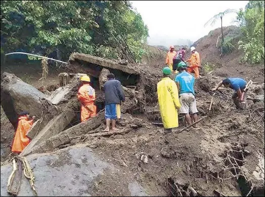  ??  ?? Handout photo shows rescuers looking for survivors yesterday after a landslide buried a DPWH building in Natonin, Mountain Province at the height of Typhoon Rosita.