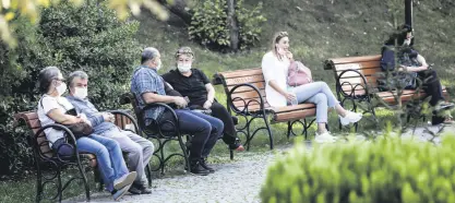  ??  ?? People wearing protective masks sit on benches in Kuğulu Park, in the capital Ankara, Turkey, Oct. 12, 2020.