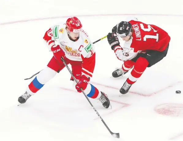  ??  ?? Russia's Vasili Podkolzin, left, and Austria's Luis Lindner battle at IIHF World Junior Hockey Championsh­ip action in Edmonton Dec. 29.