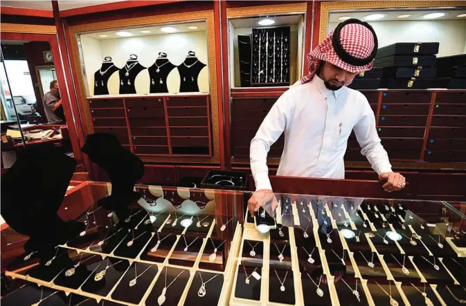  ??  ?? RIYADH: A Saudi salesman adjusts diamonds pendants at his jewelry shop in Tiba market. —AFP