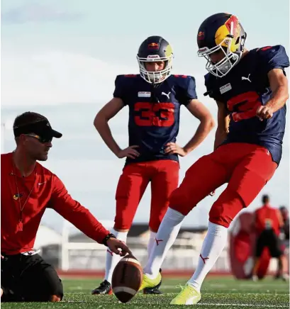  ?? — AFP ?? One, two, kick: Red Bull Racing’s Daniel Ricciardo of Australia kicking a football as his teammate Max Verstappen of Holland looks on at a training session with the Del Valle Cardinals high school football team ahead of the United States Grand Prix.