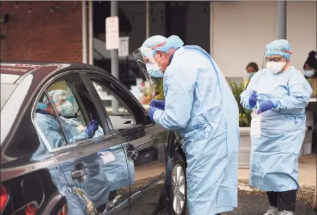  ?? Brian A. Pounds / Hearst Connecticu­t Media ?? Dentist Tom McManus and dental hygienist Ana Dacosta administer a COVID-19 swab test outside the Commuinity Health Center of Danbury on Delay Street in Danbury on Oct. 13.