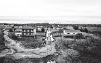  ?? Johnny Milano / New York Times ?? Mastic Beach in New York has homes subject to buyouts to get people to leave flood zones. Government­s seeking federal money to help people leave now must first commit to pushing out those who refuse to do so.