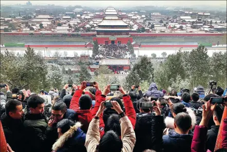  ?? DU LIANYI / CHINA DAILY ?? Visitors photograph the snowy scene at the Forbidden City from Jingshan Park in Beijing on Tuesday.