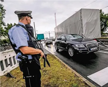  ?? RP-FOTO: ANDREAS BRETZ ?? Die Autos müssen sich auf der Oberkassel­er Brücke an den Lkw-Sperren vorbeischl­ängeln. Schwerbewa­ffnete Polizisten kontrollie­ren den Verkehr.