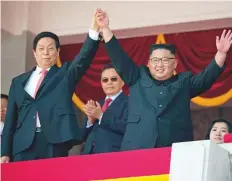  ?? AP ?? Kim Jong-un raises the hand of China’s third highest ranking official, Li Zhanshu, during the parade yesterday.