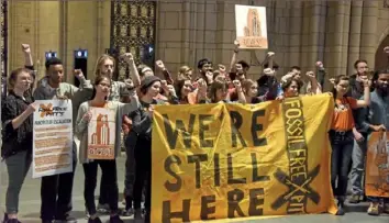  ?? Darrell Sapp/Post-Gazette ?? Members of the Fossil Free Pitt Coalition protest in the Cathedral of Learning on Friday at the University of Pittsburgh campus in Oakland.
their social media. “We are demanding an end to the funding of fossil fuels.”
