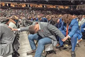  ?? POOL PHOTO BY ERIN EDGERTON ?? Members of the football team pray during the memorial service for three slain University of Virginia players at John Paul Jones Arena.