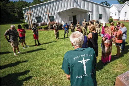  ?? PHOTOS BY STEPHEN B. MORTON / FOR THE AJC ?? Summertown Food Pantry volunteer Paul Pierre leads a group in prayer recently, blessing food they are about to give to 116 people lined up in cars nearby. Summertown families have to drive more than 10 miles into Swainsboro to get groceries from Walmart or Harveys, a smaller supermarke­t chain.