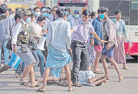  ?? — AFP photo ?? Pro-military supporters, including one (left) brandishin­g a knife, stand over a resident (centre bottom) after attacking him during a rally in Yangon following weeks of mass demonstrat­ions against the military coup.