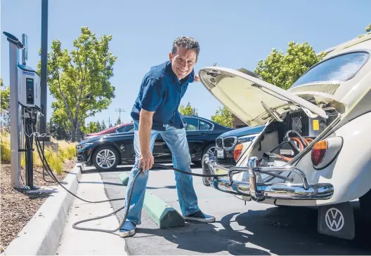  ?? IRFAN KHAN/LOS ANGELES TIMES ?? Mark Wagner, who converted his 1962 VW Beetle ragtop from gas to electric, charges it April 19 at a charging station in Irvine, California.