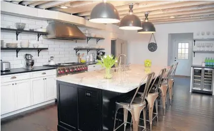  ??  ?? Silhan and Chad Stockton had the kitchen of their home completely remodeled, exposing the ceiling beams and adding granite countertop­s, an oversized island, open shelving and a six-burner range with a double oven.