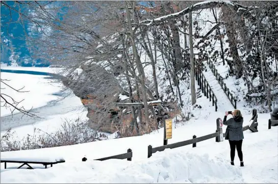  ?? ANTONIO PEREZ/CHICAGO TRIBUNE PHOTOS ?? A visitor photograph­s the icy Rock River and the St. Peter sandstone aquifer that makes up the “castle rocks” at the a scenic overlook at Castle Rock State Park in Oregon, Illinois.