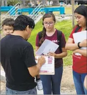  ?? Liz Moughon Los Angeles Times ?? YOUTH volunteers America Barrera and Jimena Flores speak to residents in L.A.’s MacArthur Park about the importance of participat­ion in the census.