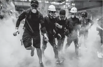  ?? Lam Yik Fei / New York Times ?? Protesters flee clouds of tear gas that riot police deployed during a march that had been billed as “family friendly.” The march was the first in a series of acts of defiance scheduled for Saturday.