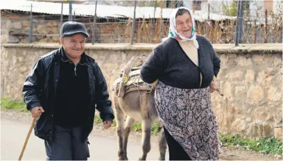  ?? Picture: AFP ?? BULGARIANS OR MACEDONIAN­S? A man and a woman chat as she leads a donkey along a street in the village of Pustec, southeaste­rn Albania, recently.