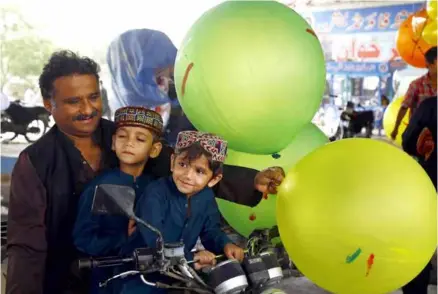  ?? ?? FESTIVE AIR: A man holds balloons for children on the first day of Eid al-fitr in Karachi, southern Pakistan.