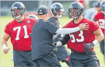  ?? CURTIS COMPTON / CCOMPTON@AJC.COM ?? Coach Dan Quinn works with offensive guards Wes Schweitzer (71) and Ben Garland on the first day of team practice on Thursday at the Falcons’ training camp in Flowery Branch.