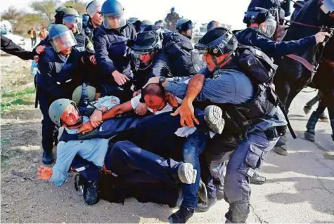  ?? AFP ?? Israeli policemen detain a Bedouin man during clashes that followed a protest against home demolition­s yesterday in the Bedouin village of Umm Al Hiran, which is not recognised by the Israeli government, near the southern city of Beersheba, in the...