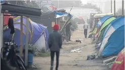  ?? Picture: AP. ?? People walk along the ‘street’ in the makeshift camp near Calais.