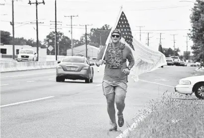  ?? AMY DAVIS/BALTIMORE SUN ?? Justin Acerboni of San Diego, one of 70 runners participat­ing in the 240-mile 9/11 Promise Run, jogs along the shoulder of Pulaski Highway in White Marsh. The runners, each doing 6-mile relays, started at the 9/11 Pentagon Memorial in D.C. on Monday morning and plan to arrive at Ground Zero in New York City on Wednesday.