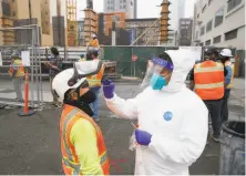  ?? Paul Chinn / The Chronicle ?? Armando Vidrio collects a sample from a constructi­on worker during onsite coronaviru­s testing for Build Group employees.