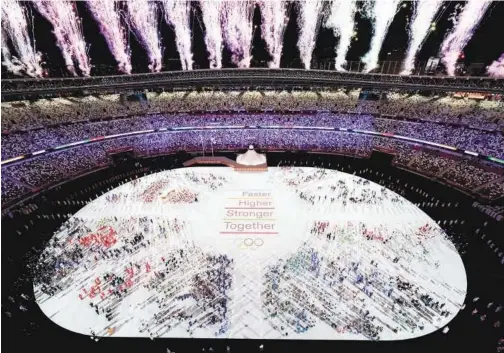  ?? Associated Press ?? ↑
Athletes gather at the stage as fireworks light up the sky during the opening ceremony of 2020 Tokyo Games on Friday.