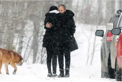  ?? DARREN MAKOWICHUK / POSTMEDIA NEWS ?? A family member is hugged as RCMP investigat­e a home in Morley, Alta., Wednesday where a small infant died and 13 children and an adult were taken to hospital in Calgary.