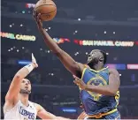  ?? MARK J. TERRILL/ ASSOCIATED PRESS ?? Golden State’s Draymond Green, right, shoots over L.A. Clippers center Marcin Gortat on Monday night. Green was suspended by Golden State for Tuesday’s game against Atlanta.