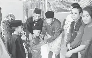  ??  ?? TERIMALAH: Azman (empat kanan) menyerahka­n duit raya kepada anak yatim dan kanak-kanak yang hadir pada majlis itu.