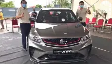  ??  ?? Kim Hoon (le ) and Kereta Mewah sales manager Kenn Tan give their thumbsup for the newly-launched Proton X50.