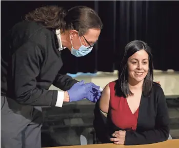  ?? PHOTOS BY ERIC SEALS/DFP ?? Robert Dunne, medical director for the city of Detroit and the Detroit Fire Department, left, gives the first dose of the Moderna vaccine to UAW Vice President Cindy Estrada on Tuesday.