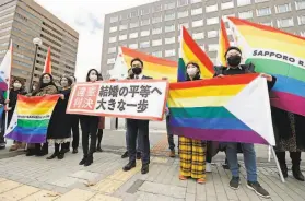  ?? Yohei Fukai / Associated Press ?? Plaintiffs’ lawyers and supporters outside a courtroom in Sapporo, northern Japan, hold rainbow flags and a banner reading: “Unconstitu­tional judgment.”