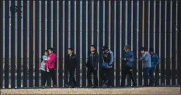  ?? JOHN MOORE/GETTY IMAGES ?? Undocument­ed immigrants walk along the U.S.-Mexico border wall after they ran across the shallow Rio Grande into El Paso on March 17 in Ciudad Juarez, Mexico.