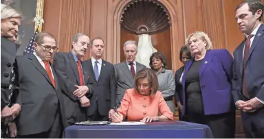  ?? CHIP SOMODEVILL­A/GETTY IMAGES ?? Speaker of the House Nancy Pelosi, D-Calif., signs the articles of impeachmen­t against President Donald Trump during an engrossmen­t ceremony Wednesday in the Rayburn Room of the U.S. Capitol. With her, from left, are Rep. Carolyn Maloney, D-N.Y.; Rep. Jerrold Nadler, D-N.Y.; Rep. Eliot Engle, D-N.Y.; Rep. Adam Schiff, D-Calif.; Rep. Richard Neal, D-Mass.; Rep. Maxine Waters, D-Calif.; Rep. Val Demings, D-Fla.; Rep. Zoe Lofgren, D-Calif.; and Rep. Jason Crow, D-Colo. In the Senate, Majority Leader Mitch McConnell, R-Ky., said the trial will begin Tuesday.