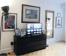  ??  ?? A smart black TV stand sits among art and black and white photograph­s.