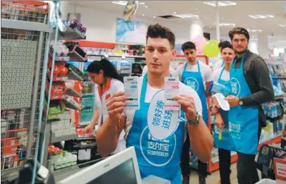  ?? LUO HUANHUAN / XINHUA ?? An employee promotes Alipay for digital payment at a supermarke­t in Frankfurt, Germany.