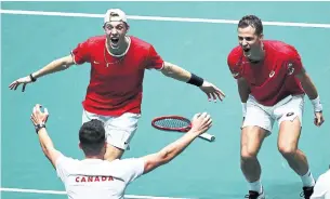  ?? CLIVE BRUNSKILL GETTY IMAGES ?? Denis Shapovalov, left, and Vasek Pospisil celebrate with captain Frank Dancevic after defeating Australia in doubles to clinch their quarterfin­al tie at the Davis Cup Finals in Madrid on Thursday.