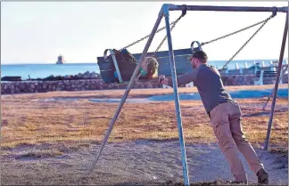  ?? TIM MARTIN/ THE DAY ?? John Carton of Groton gives his stepdaught­er Natalie Babcock a push at Eastern Point Beach in Groton on Thursday. The two stayed at the playground as long as they could, but temperatur­es were hovering around the freezing mark, with strong winds,...