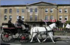  ?? KIRSTY WIGGLESWOR­TH - THE ASSOCIATED PRESS ?? A horse drawn carriage passes decorated houses along the route that the carriage carrying Prince Harry and Meghan Markle will take after their marriage, in Windsor, England Friday. Britain’s Prince Harry and Meghan Markle will marry in Windsor today.