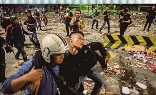  ?? REUTERS PIC ?? An injured police officer being carried away by his colleagues during clashes with protesters in Jakarta yesterday.