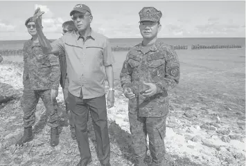  ?? FRANCE PRESSE ?? In this file photo, Defense Secretary Delfin Lorenzana (second from right) inspects an airport runway during a visit to Pag-asa Island in the Spratlys chain in the South China Sea. AGENCE