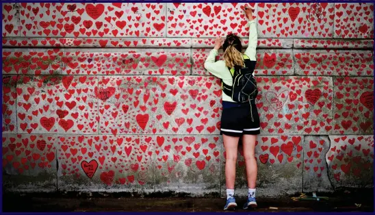  ??  ?? HEART OF THE MATTER: A youngster adds her mark to the wall of remembranc­e for Covid victims on the Embankment in London