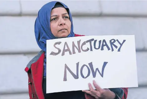  ?? FOTO: AP ?? „Zuflucht jetzt“steht auf dem Plakat, das eine Demonstran­tin in San Francisco hochhält. Die kalifornis­che Metropole hat sich bereits 1989 zur „Zufluchtss­tadt“erklärt. Einige Hundert gibt es davon in den USA. Präsident Donald Trump will ihnen staatliche...