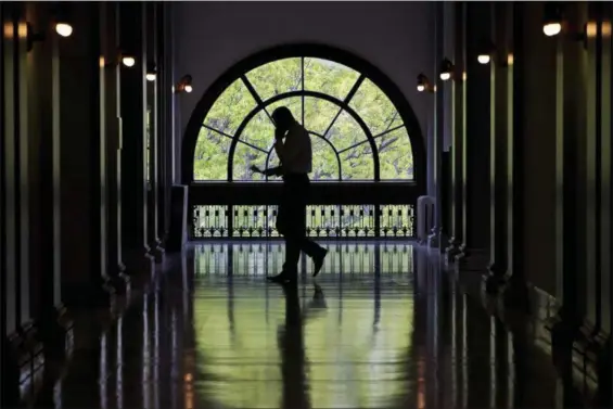  ?? JACQUELYN MARTIN — THE ASSOCIATED PRESS FILE ?? A Capitol Hill staffer looks down at papers while on a cell phone while walking inside the Russell Senate Office Building on Capitol Hill in Washington. The Department of Homeland Security acknowledg­es detecting suspected cell tower simulators in...