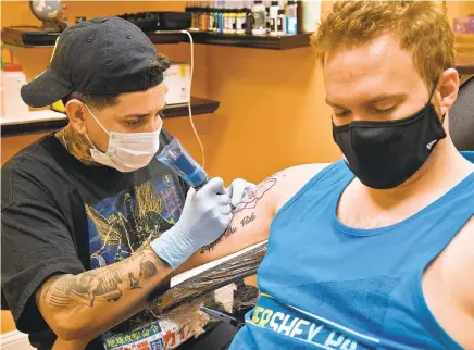  ?? PAUL W. GILLESPIE/BALTIMORE SUN MEDIA PHOTOS ?? Tattoo artist Carlos Escobar works on Elliott Trenary on Aug. 24. Tattoo artists at Lucky Bird Tattoo in Riva have been working with increased demand during much of the COVID-19 pandemic.