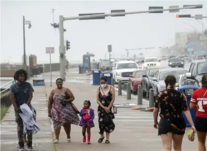  ??  ?? A group of people walk along Seawall Boulevard as heavy winds arrive in Galveston last Saturday. Photograph: Godofredo A Vásquez/AP